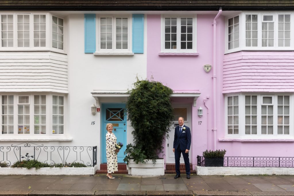 Bride and groom in front of colourful houses in Chelsea