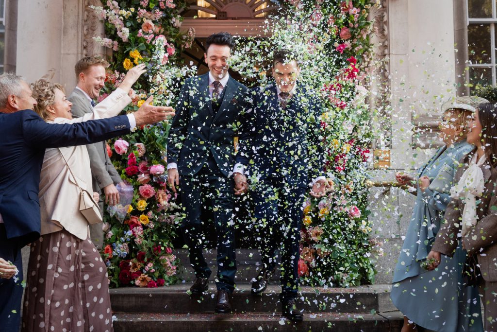 Confetti being thrown at two grooms at Chelsea Old Town Hall
