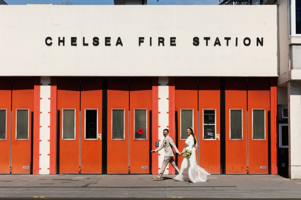 bride and groom walking in front of Chelsea Fire Station